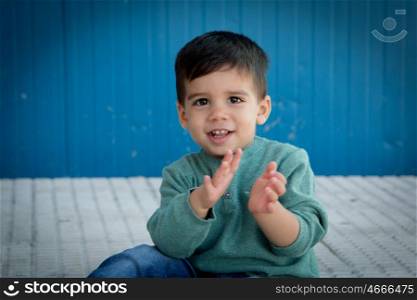 Cheerful child playing palms on the street in front of a blue wall