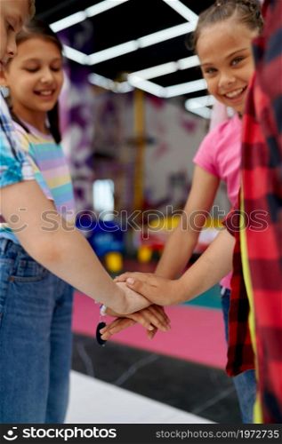 Cheerful children hold hands, top view, in entertainment center. Boys and girls having fun, kids spend the weekend on playground, happy childhood. Children hold hands on playground, top view