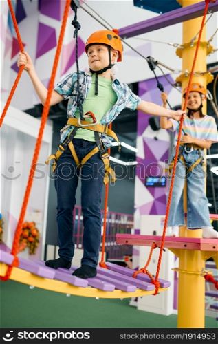 Cheerful children on zip line in entertainment center. Boy and girl having fun in climbing area, kids spend the weekend on playground, happy childhood. Happy children on zip line in entertainment center
