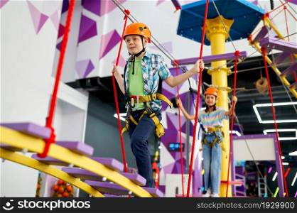 Cheerful children on zip line in entertainment center. Boy and girl having fun in climbing area, kids spend the weekend on playground, happy childhood. Happy children on zip line in entertainment center