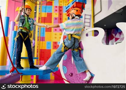 Cheerful children on zip line in entertainment center. Boy and girl having fun in climbing area, kids spend the weekend on playground, active childhood. Happy children on zip line in entertainment center