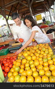 Cheerful couple choosing fruits in outdoor market