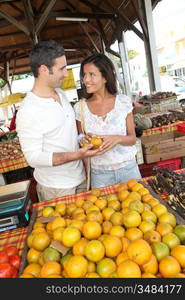 Cheerful couple choosing fruits in outdoor market