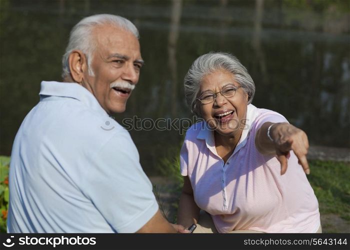 Cheerful couple enjoying at park , woman pointing at something