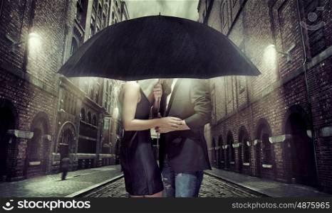 Cheerful couple hiding themselves under the umbrella