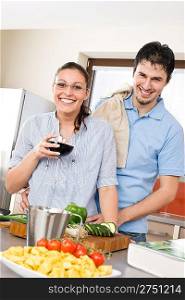 Cheerful couple in modern kitchen cook together, drink red wine