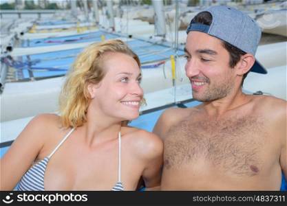 cheerful couple laying next to sailboats