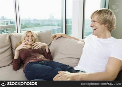 Cheerful couple relaxing on sofa at home