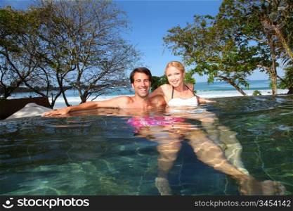 Cheerful couple swimming in resort pool