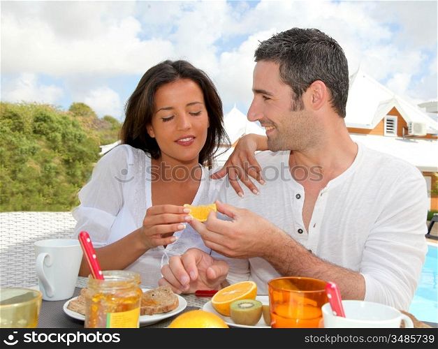 Cheerful couple taking breakfast on the outdoor terrace