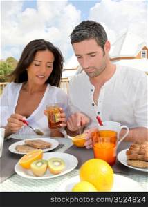 Cheerful couple taking breakfast on the outdoor terrace