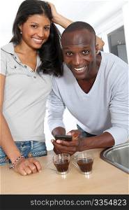Cheerful couple using smartphone while taking coffee