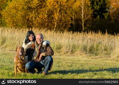 Cheerful couple with retriever dog in autumn countryside sunset