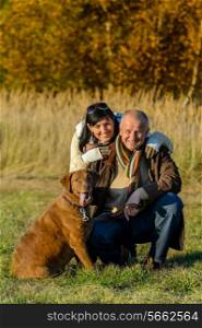 Cheerful couple with retriever dog in autumn park sunset