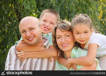 cheerful family. dad, mom, little boy and girl in early fall park. son is embracing father and daughter is embracing mother