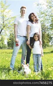 Cheerful family in summer sunny park walking on grass with dog. Cheerful family in park