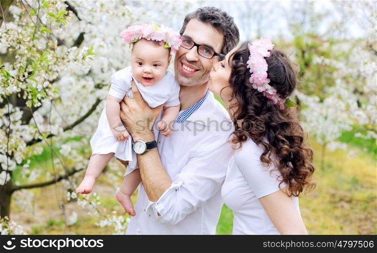 Cheerful family in the spring apple tree orchard