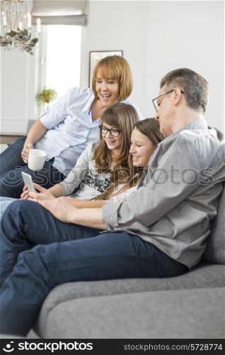 Cheerful family using tablet PC on sofa at home