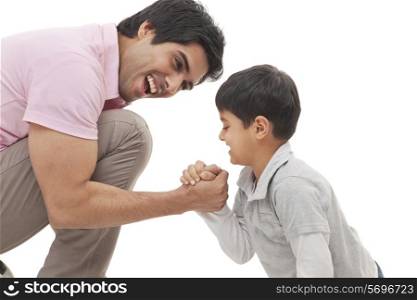 Cheerful father and son arm wrestling over white background