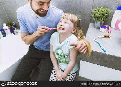 cheerful father helping daughter brush teeth