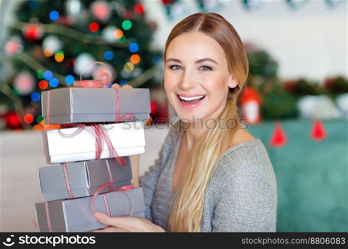 Cheerful female at home in beautiful festive decorated room, holding gift boxes, happy Christmas holidays. Cheerful female with Christmas gifts