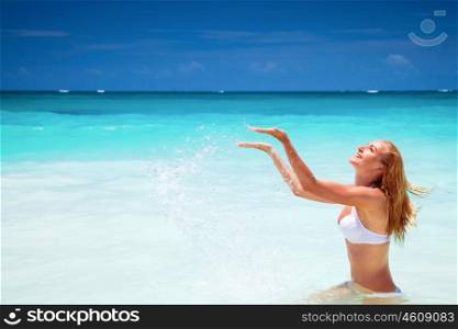 Cheerful female on the beach, splashing refreshing water, enjoying summer holidays on the beach resort, happy active lifestyle