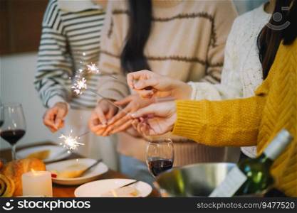 Cheerful friends enjoying home Birthday holiday party. Asian Friends hold lights with sparkling Sparkler celebrating Christmas or New Year eve party