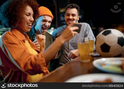 Cheerful friends having fun watching football game on smartphone at sport bar. Extremely emotional young people drinking draft beer at bar counter in pub. Cheerful friends having fun watching football game on smartphone at sport bar