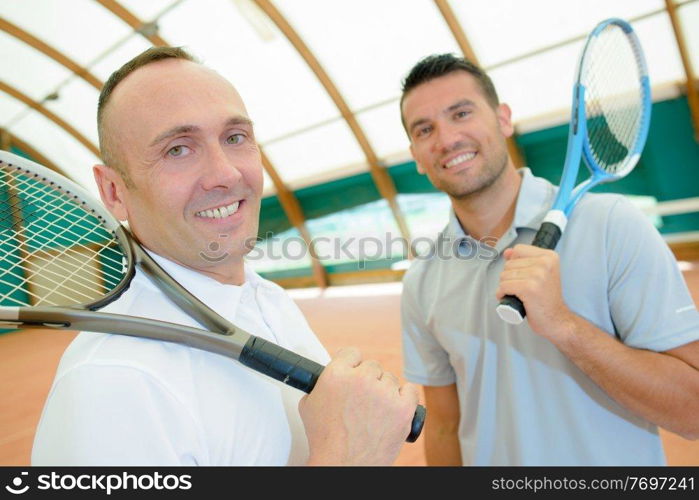 cheerful friends posing before indoor tennis match