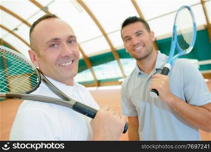 cheerful friends posing before indoor tennis match