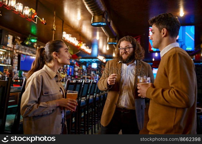Cheerful friends talking drinking draft beer in pub. Young people rest having nice conversation standing at bar counter. Football fans meeting. Cheerful friends talking drinking draft beer in pub