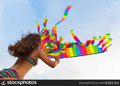 Cheerful girl flies a kite on the beach. Enjoying active games outdoors. Beach activities. Happy summer holidays.. Happy girl with kite on the beach