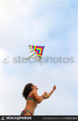 Cheerful girl flies a kite on the beach. Enjoying active games outdoors. Beach activities. Happy summer holidays.. Activities for kids on the beach