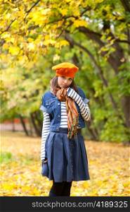Cheerful girl in orange beret in autumn forest