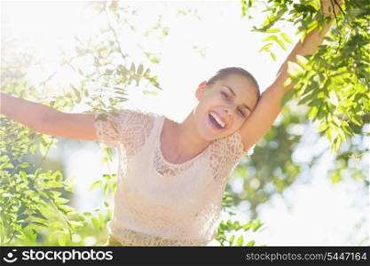 Cheerful girl playing in foliage in forest