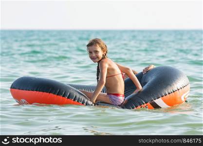 Cheerful girl rides on an inflatable boat at sea