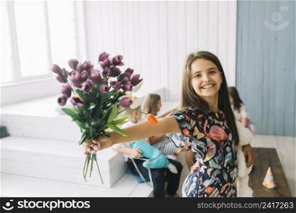 cheerful girl showing bouquet birthday party