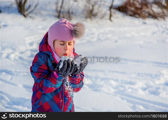 Cheerful girl throws snow on a sunny winter day. Active games with snow. The winter vacation. Happy childhood.. Cheerful girl throws snow on a sunny winter day. Active games with snow. The winter vacation.