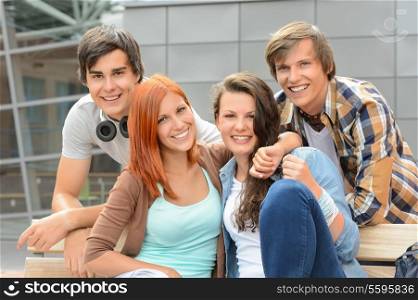 Cheerful group of student friends hugging together outside college