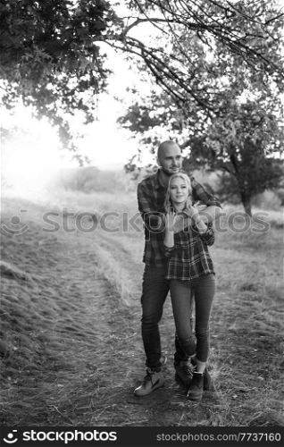 Cheerful guy with a board and a blonde girl for a walk in plaid shirts at sunset