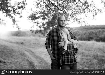 Cheerful guy with a board and a blonde girl for a walk in plaid shirts at sunset