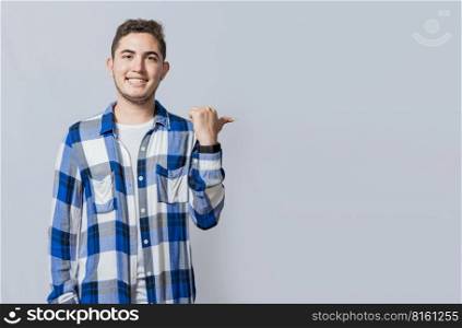 Cheerful guy with friendly smile pointing to the side isolated. Smiling young man pointing with one hand a promotion to the side. Concept of handsome man pointing an advertisement isolated