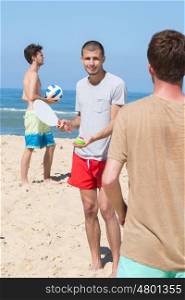 cheerful happy friends relaxing at beach and playing with rackets