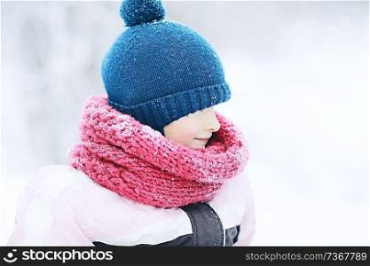 cheerful happy little girl on winter walk / little girl smiles and laughs in snow, plays winter for a walk. The concept of happy childhood. Warm sportswear down jacket, mittens, children&rsquo;s shoes