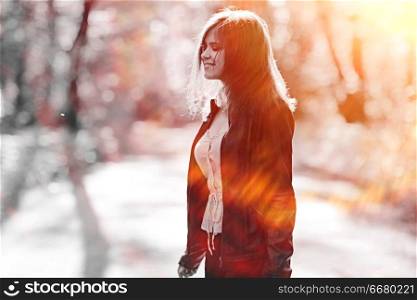 Cheerful happy young adult girl in sunlight rays and wind hair