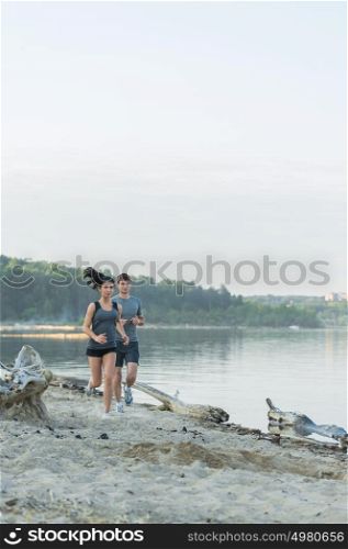 Cheerful Hispanic Caucasian couple running on beach at morning