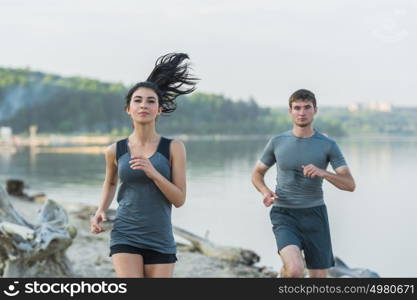 Cheerful Hispanic Caucasian couple running on beach at morning