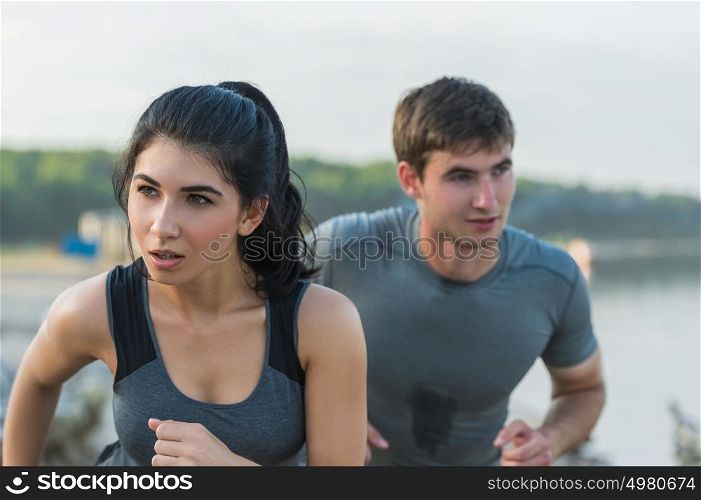 Cheerful Hispanic Caucasian couple running on beach at morning