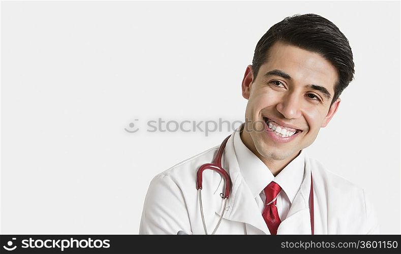 Cheerful Indian male doctor looking sideways over light gray background
