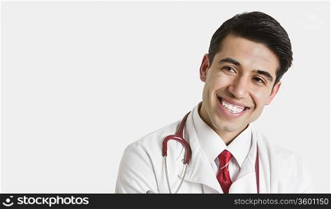 Cheerful Indian male doctor looking sideways over light gray background